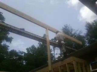 Carpenter setting a ridge beam over a new addition frame — Ice Dam Removal by Roofing Brothers in Douglass