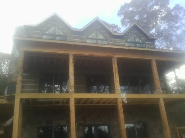 Dormers and porch framing on a large log home under construction — Roof Coating work by our crew in Douglass