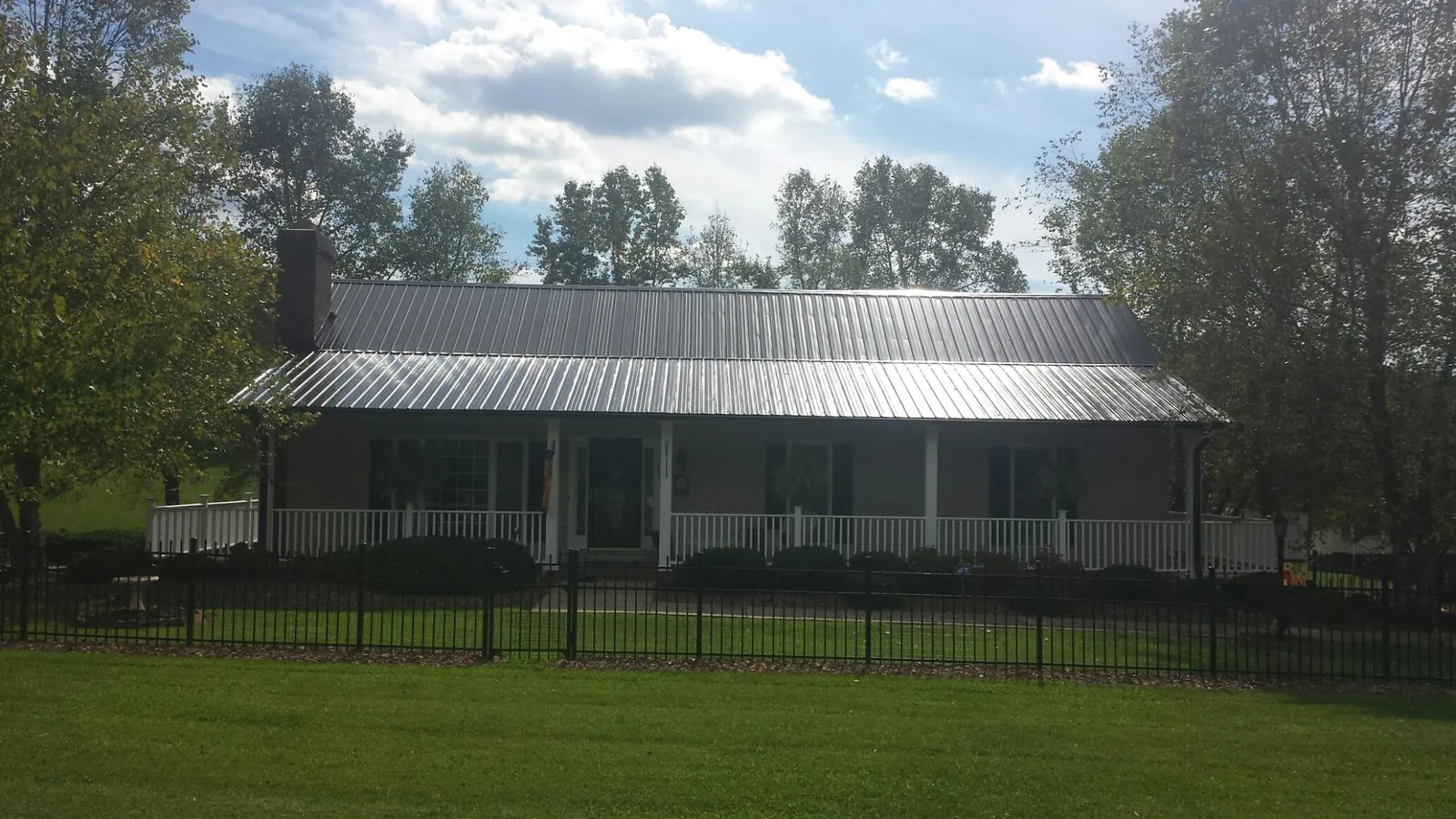 Gray metal roof on a brick ranch with a full width front porch — Gutter Guard Installation work by our crew in Douglass